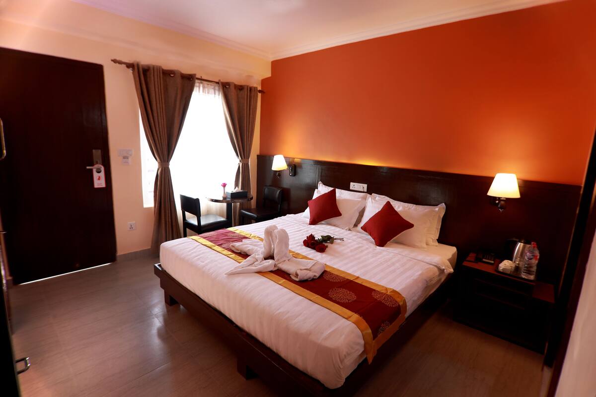 Une chambre d’hôtel avec un grand lit, une table de chevet, une lampe et une vue sur l’extérieur.