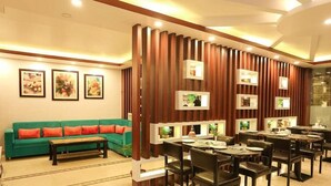 Un área de comedor moderna con un sofá verde, pared de paneles de madera y cuadros enmarcados.