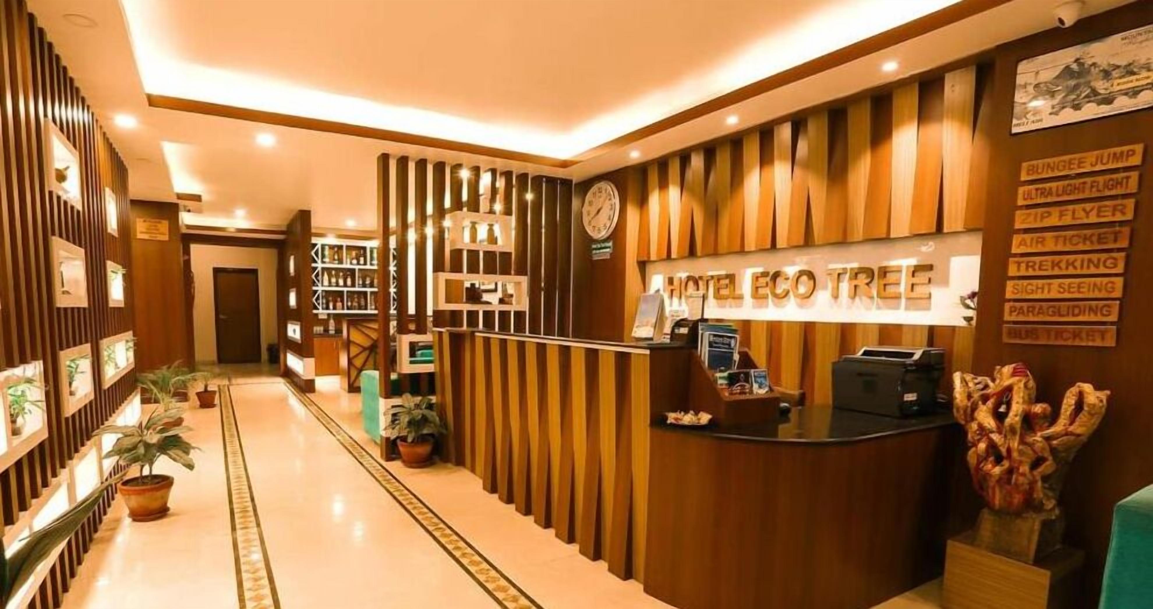 Un espace d’accueil d’hôtel avec un comptoir de réception en bois, une horloge et un panneau indiquant les activités proposées, comme le saut à l’élastique et les randonnées.