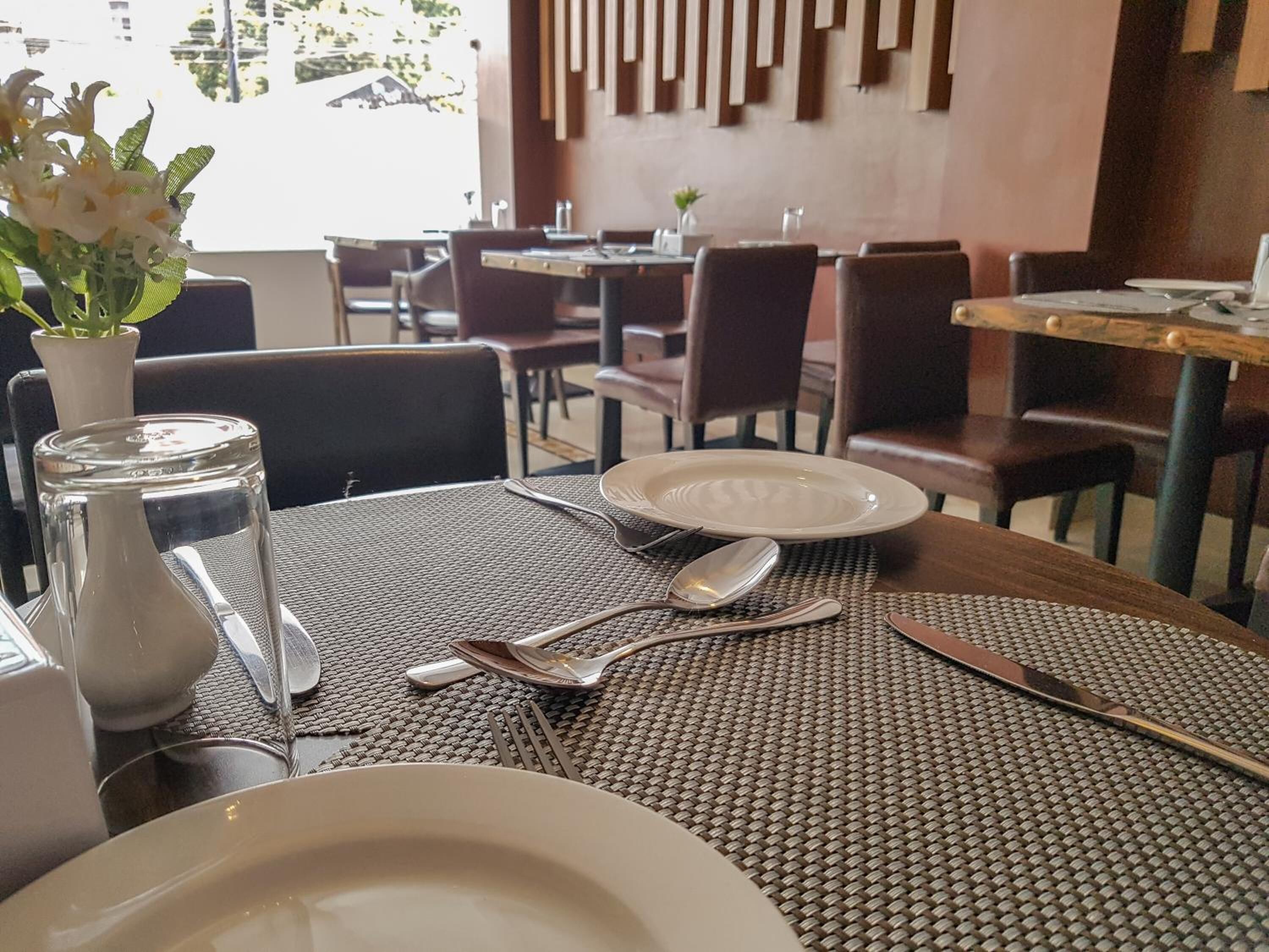 A dining table set with plates, cutlery, and a vase of flowers in a restaurant.