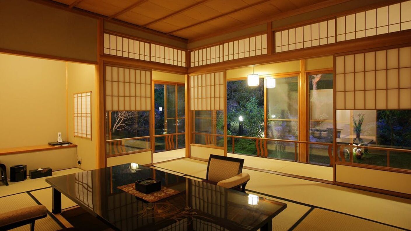 A traditional Japanese room with tatami flooring, sliding doors, and a low table with cushions.