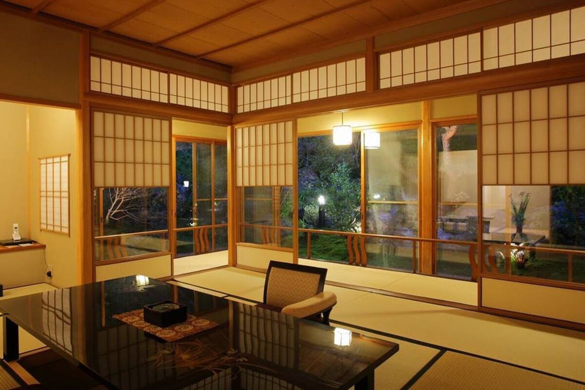 A traditional Japanese room with tatami flooring, sliding doors, and a low table with cushions.