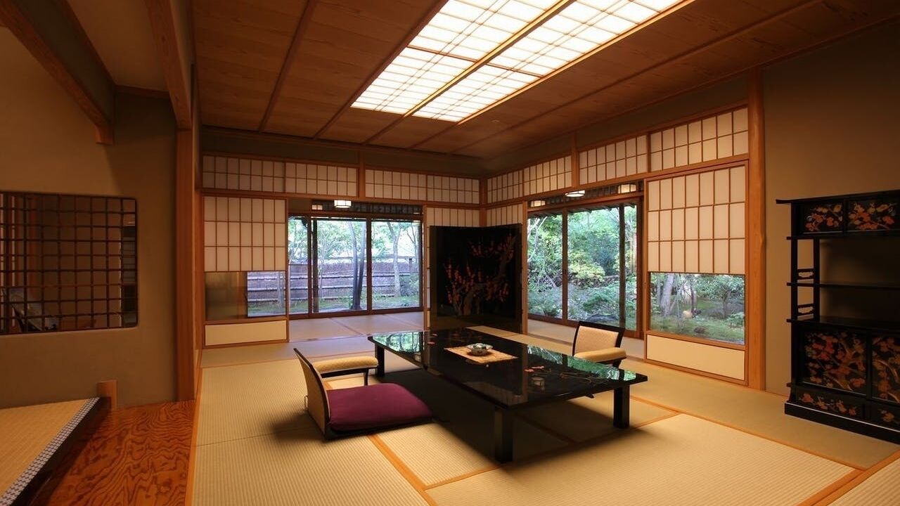 Une pièce de style japonais traditionnel, avec un sol recouvert de tatamis, une table basse avec des coussins et des portes coulissantes.