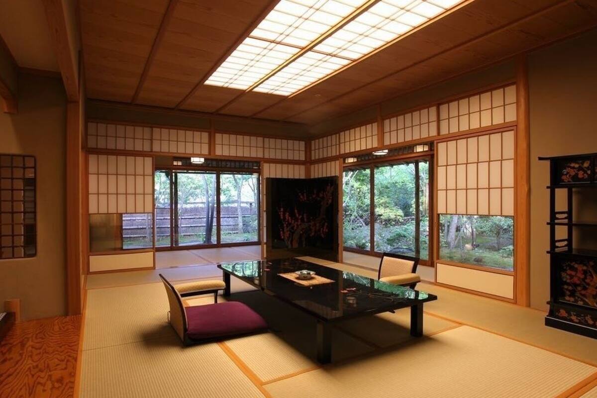 A traditional Japanese room with tatami flooring, a low table with cushions, and sliding doors.