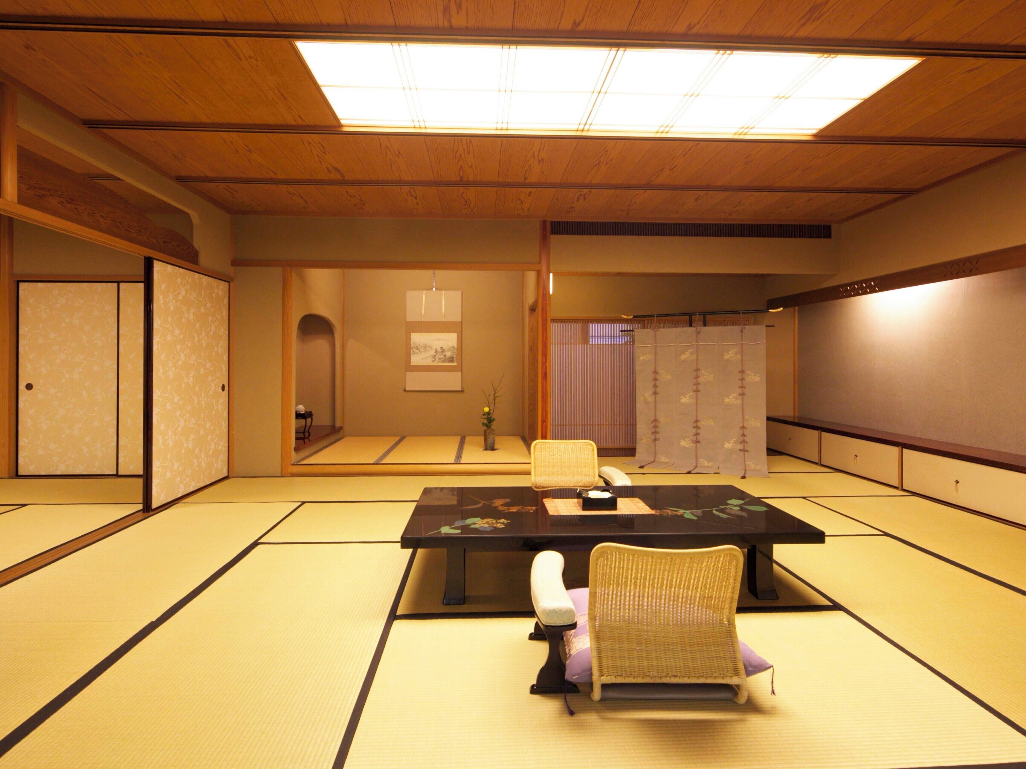 A traditional Japanese room with tatami flooring, a low table, and two chairs.