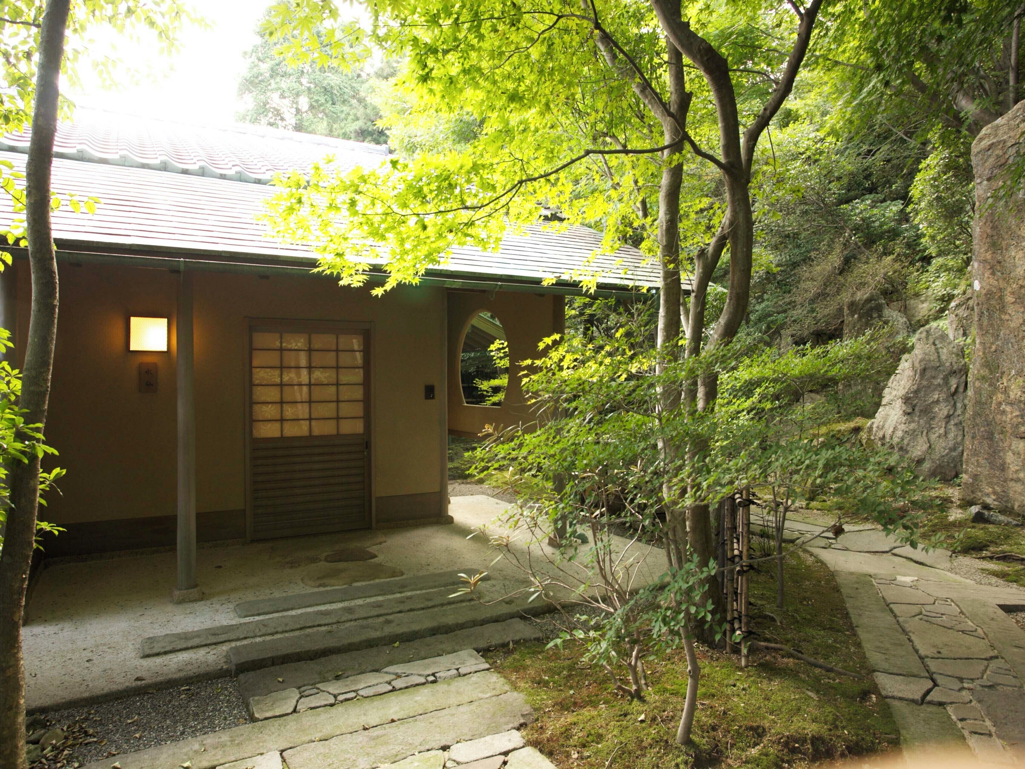 A traditional building with a tiled roof, a wooden door, and a stone pathway leading to it.