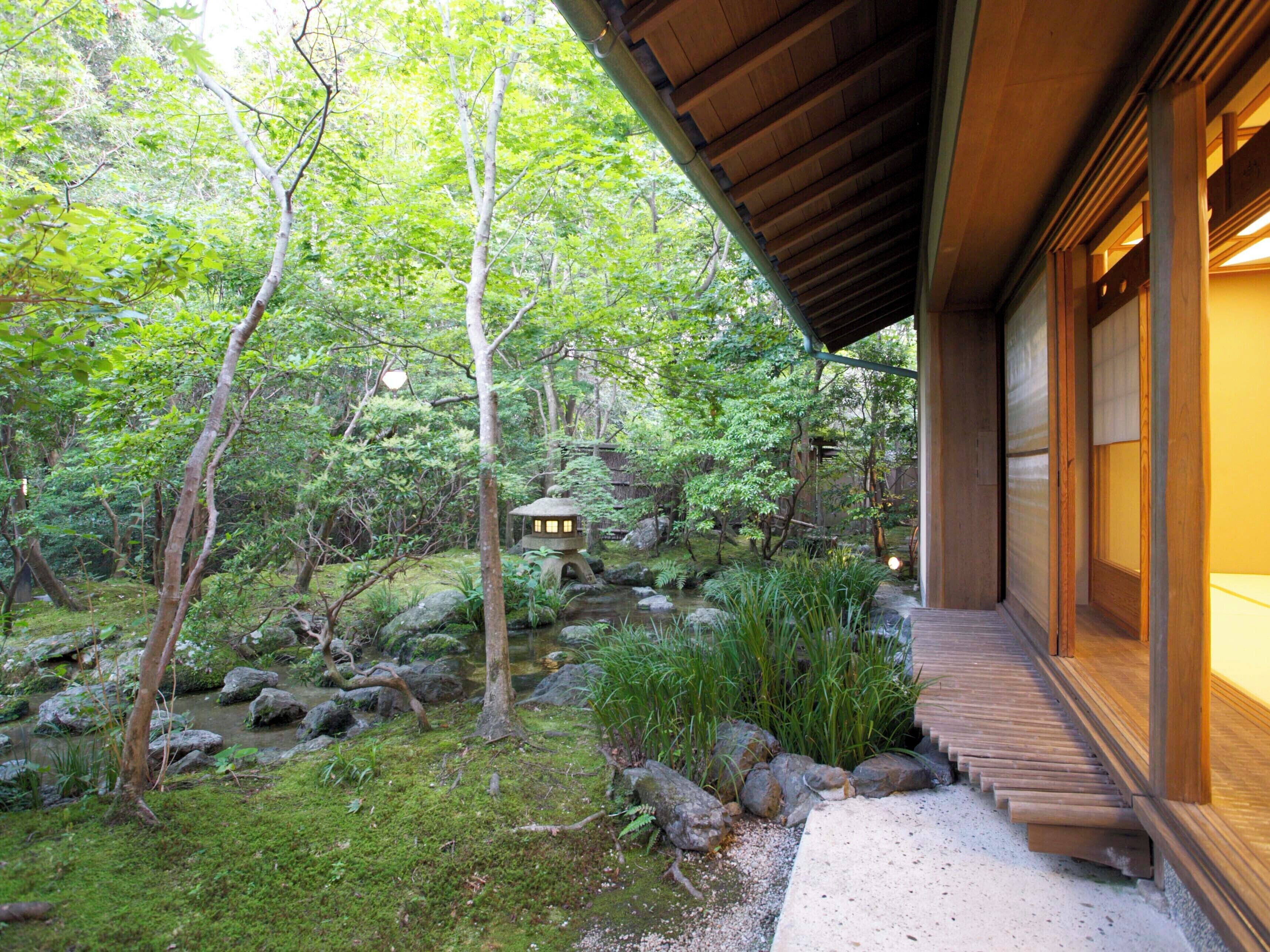 A traditional Japanese-style building with a wooden exterior and a stone pathway leading to a small pond with a stone lantern.