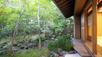 A traditional Japanese-style building with a wooden exterior and a stone pathway leading to a small pond with a stone lantern.