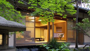 Un interior tradicional japonés con esteras de tatami, una mesa baja y vista a un estanque de carpas.