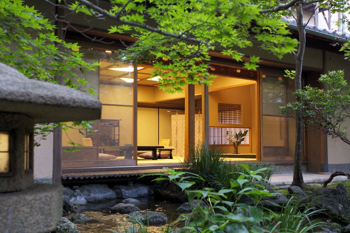 A traditional Japanese-style interior with tatami mats, a low table, and a view of a koi pond outside.
