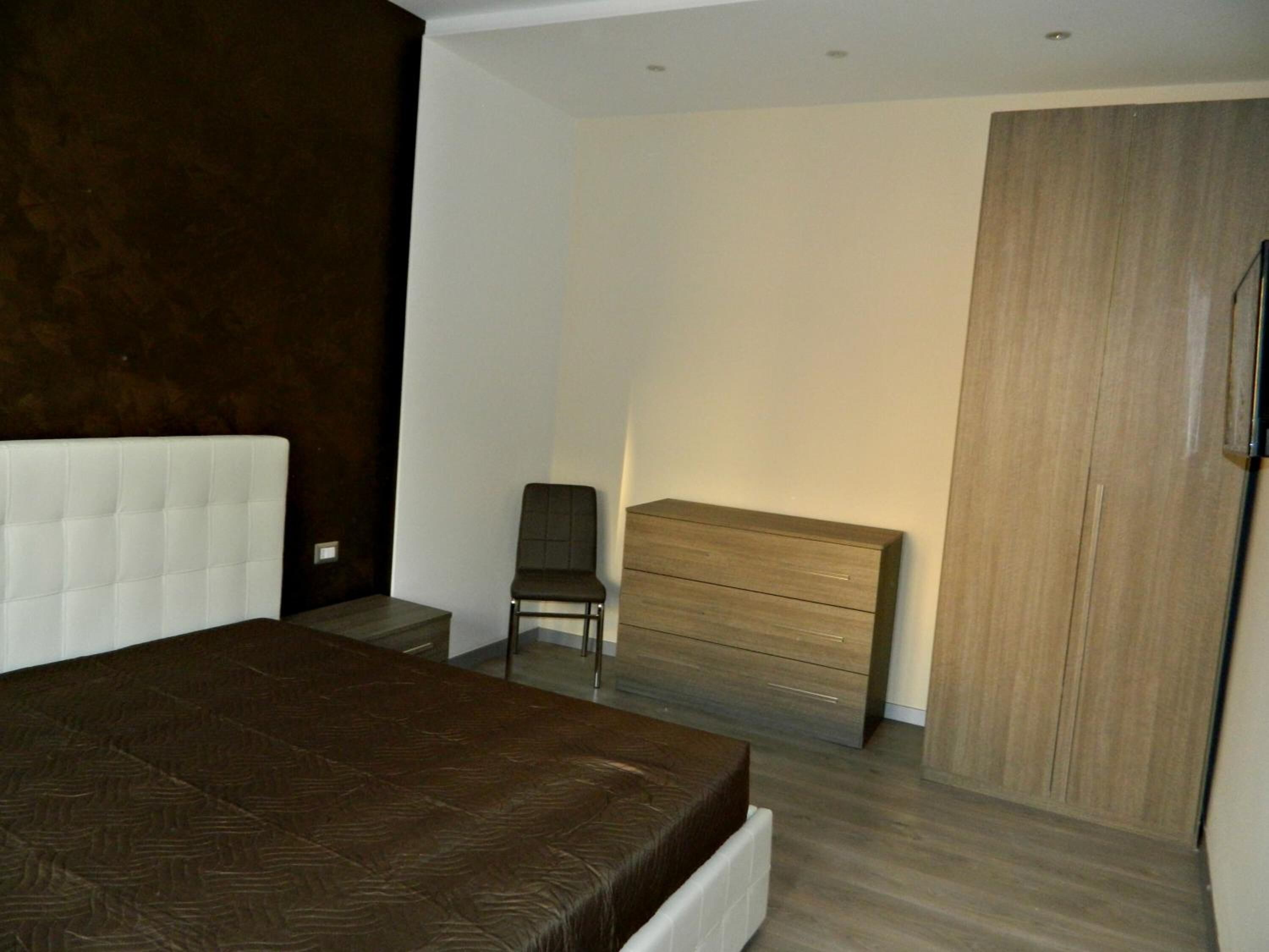 Une chambre à coucher avec un grand lit, une commode en bois, une chaise et une armoire.