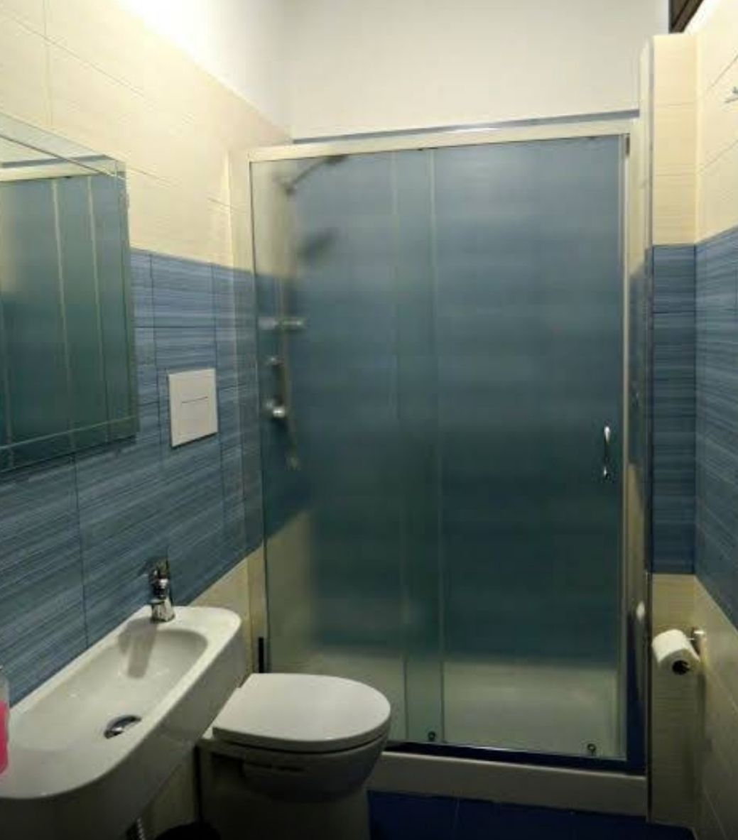 A bathroom with a glass shower enclosure, a sink, and a toilet.