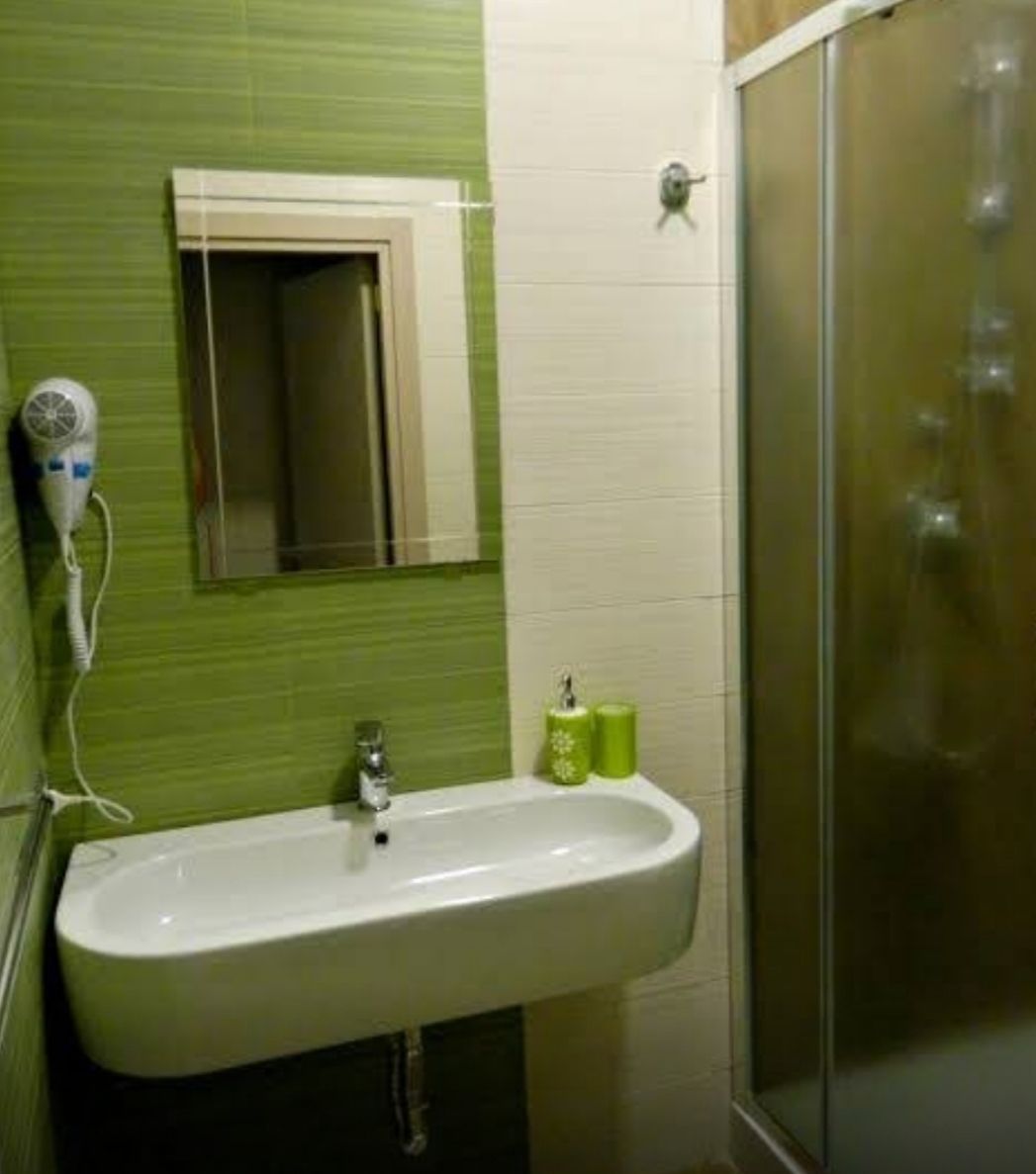 A bathroom with a sink, a mirror, a hairdryer, and a shower.