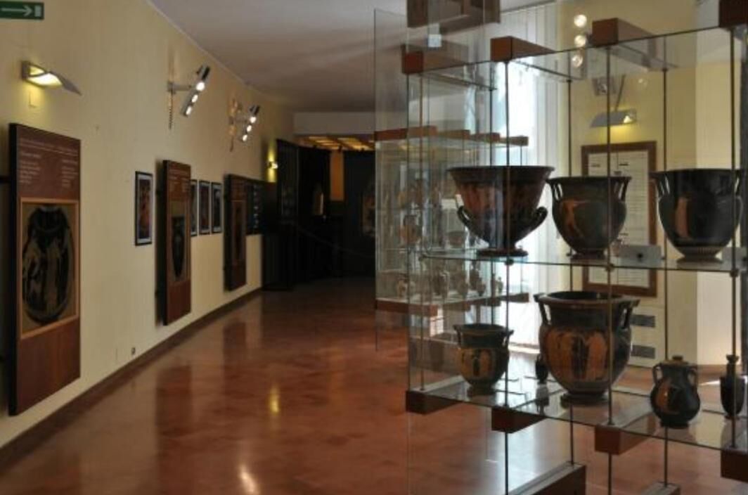 A museum corridor with glass display cases containing ancient pottery.