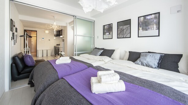 Una habitación de hotel moderna con una cama grande, un área de estar separada y vistas al pasillo.