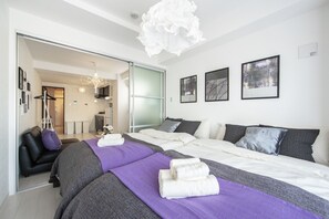 Una habitación de hotel moderna con una cama grande, un área de estar separada y vistas al pasillo.