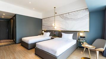 A modern hotel room with two beds, a small table, and a chair.