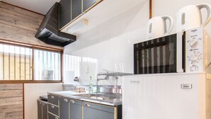 A modern kitchen with a black and white color scheme, a built-in oven, and a refrigerator. - Bar Hostel Shikanzima (Osaka)