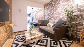 A modern living room with a sofa, coffee table, and a brick-patterned wall. - Bar Hostel Shikanzima (Osaka)