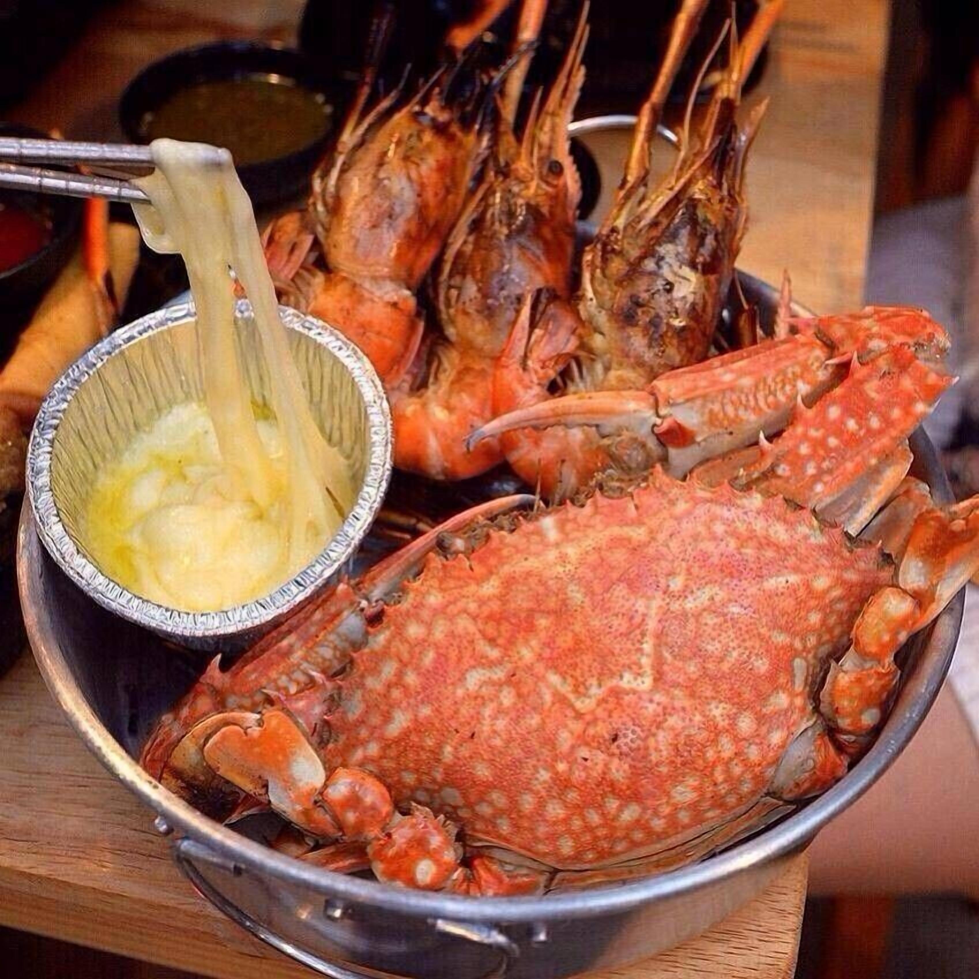 A large crab and several prawns on a metal platter.