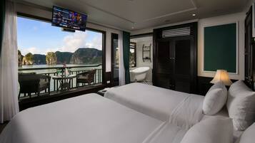 A hotel room with a balcony, a TV, a bathtub, and a view of the sea.