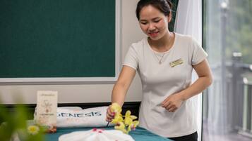 A person in a white shirt arranging flowers on a bed with a green bedspread and a white pillow labeled "GENESIS REGAL".