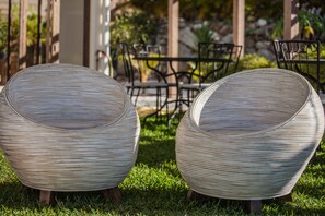 Two large, ribbed, round chairs with wooden legs on a grassy area, surrounded by outdoor furniture and plants. - Farino Lodge (Farino)