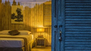 Un dormitorio con cama, mesita de noche, lámpara y un cuadro en la pared.
