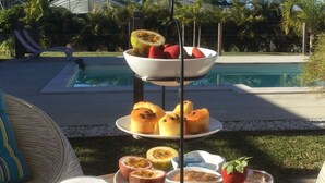 Una presentación de frutas y postres en tres niveles, con una piscina al fondo.