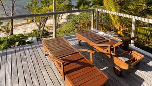 Une terrasse en bois avec une pergola, deux tables en bois et un chariot.