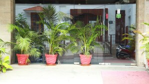 A building entrance with glass doors, potted plants, and a red motorcycle parked outside. - Mrk Inn (Puducherry)