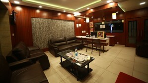 A modern living room with a leather sofa, a glass coffee table, and a dining area with a small kitchen. - Mrk Inn (Puducherry)
