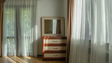 A room with a wooden dresser, a mirror, and sheer curtains.