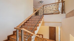 A staircase with a wooden handrail and metal balusters, leading to an upper floor. - Ariana Family Hotel (Dilijan)