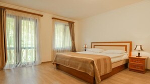 A bedroom with a wooden bed, two bedside tables, and a window with curtains. - Ariana Family Hotel (Dilijan)