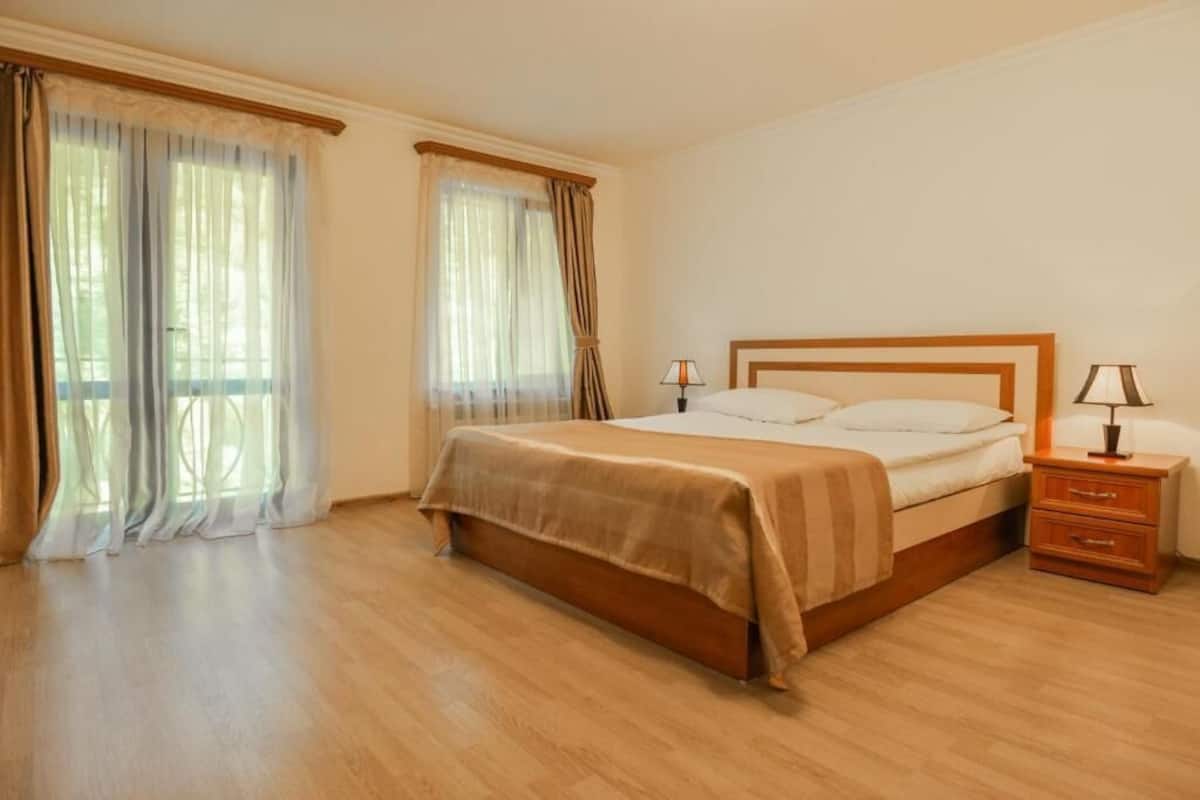 A bedroom with a wooden bed, two bedside tables, and a window with curtains.