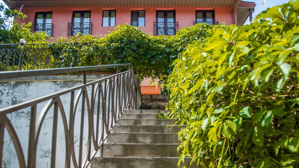 A staircase leading to a building with a pink facade and balconies. - Ariana Family Hotel (Dilijan)