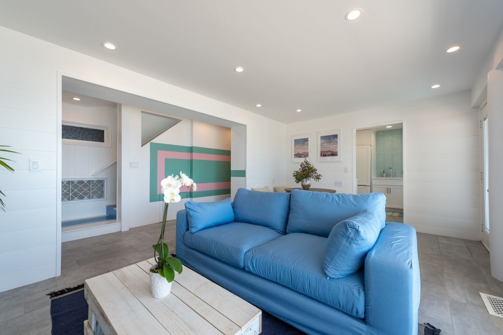 A modern living room with a blue sofa, a wooden coffee table, and a potted orchid.