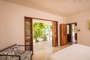 Relax in a spacious room with a large bed and access to an outdoor area with a beach view.