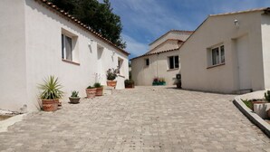 A paved courtyard with potted plants and white buildings with tiled roofs. - 2-room villa with a terrace and a view of the pool. (Fréus)