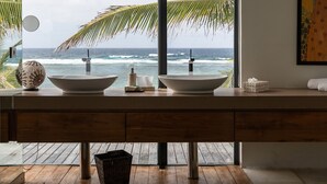 Ein modernes Badezimmer mit großem Fenster und Meerblick, Holzboden und einem Doppelwaschbecken.