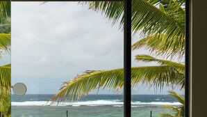 Ein Badezimmer mit zwei großen Waschschalen, einem kleinen Spiegel und Meerblick durch ein Fenster.