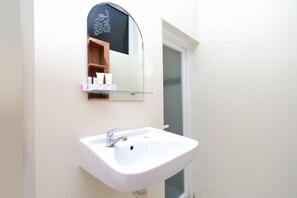 A bathroom with a white sink, a glass shelf above it, and a mirror with a decorative frame. - Hotel O Unta Residence (Semarang)