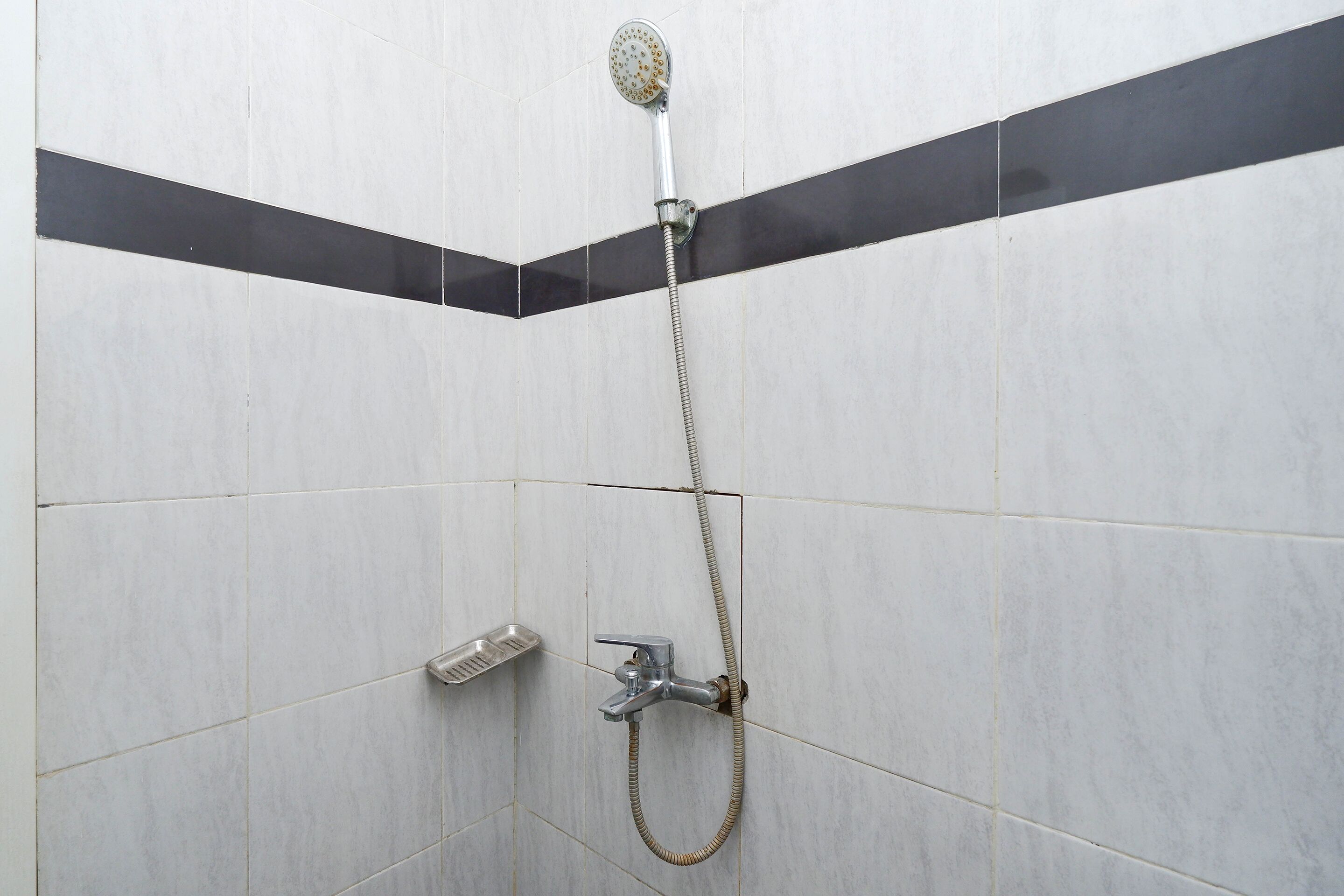 A shower with a handheld showerhead and a handheld faucet.