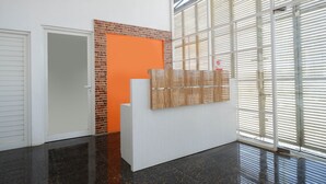 Ein Empfangsbereich mit einer weißen Theke, einer Glastrennwand und einer Wand mit Ziegelakzenten.
