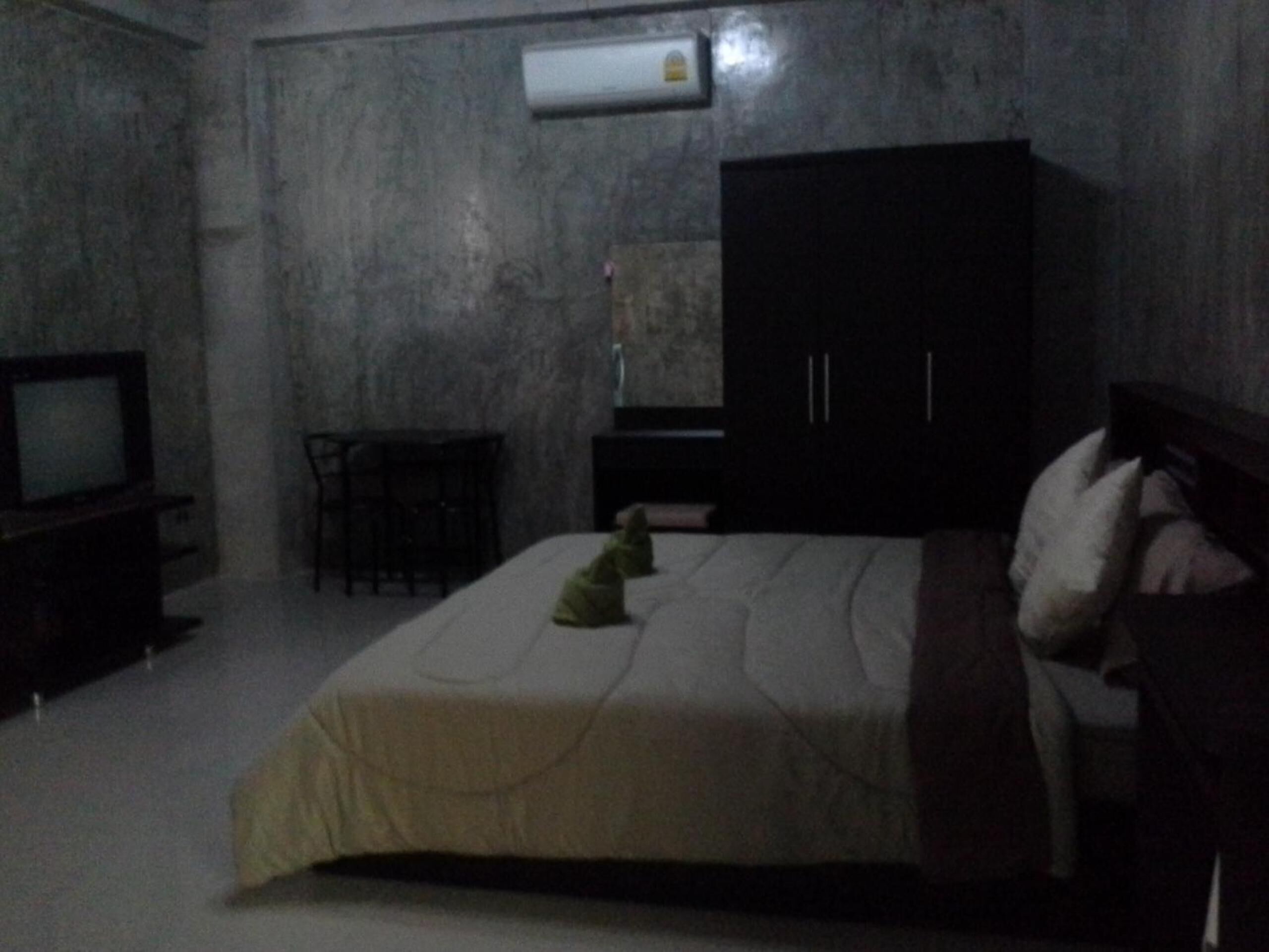 Una habitación tenuemente iluminada con una cama, un televisor y un armario.