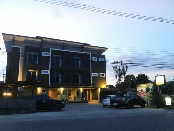 Un edificio de varios pisos con techo plano y un área de estacionamiento al frente.