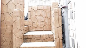 Un conjunt d'escales de pedra que condueixen a una porta, amb una paret de maó d'un costat i una paret enrajolada de l'altre.