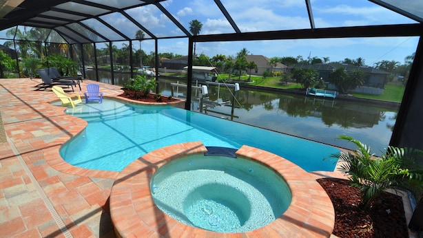 Una piscina coperta con idromassaggio, lettini prendisole e vista su una zona residenziale.