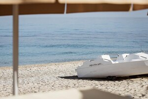 Un bote llamado 'aquabLift' en una playa de guijarros con una vista despejada del agua.